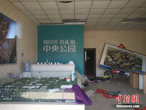 從一家已經(jīng)關(guān)門的售樓處門外望進(jìn)去,，地上散落著廢紙,、條幅，沙盤上放著落灰的殺蟲劑,。<a target='_blank' href='http://www.chinanews.com/' >中新網(wǎng)</a>記者 邱宇 攝