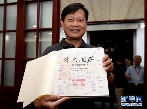 在中共一大會址紀念館內,，今年的第100萬名觀眾劉凱在展示獲贈的精裝圖冊《偉大開端》（8月25日攝）。圖冊扉頁上蓋有“第1000000名觀眾”紀念章,，還有紀念館全體工作人員的簽名,。新華社記者 劉穎 攝
