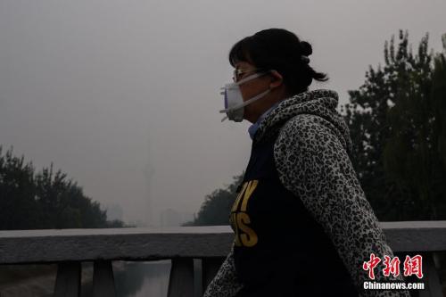 圖為10月15日,，北京一名市民戴防霾口罩在戶外行走,，遠(yuǎn)處的中央電視塔亦被霧霾籠罩,。<a target='_blank' href='http://www.chinanews.com/'>中新社</a>記者 崔楠 攝