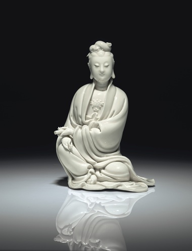 明十七世紀(jì)初 德化白釉書卷觀音坐像 《何朝宗》葫蘆形印款,，高8 58 寸 (21.9公分)。估價(jià)：60,000-80,000美元,。此拍品于2018年9月13至14日在佳士得紐約亞洲藝術(shù)周之中國(guó)瓷器及工藝精品拍賣中呈獻(xiàn),。