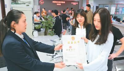 河北省承德市網(wǎng)絡(luò)代購經(jīng)營者陳晨(右)從工作人員手中接過帶有統(tǒng)一社會信用代碼的營業(yè)執(zhí)照,。 劉環(huán)宇攝(人民圖片)