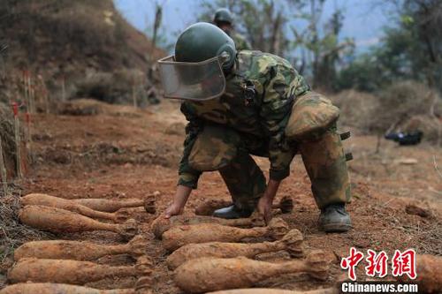 中國人民解放軍南部戰(zhàn)區(qū)陸軍云南掃雷大隊在雷場掃雷期間，一名戰(zhàn)士將一枚搜排出來的炮彈放至臨時存放點,?！蠲?攝