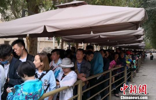 圖為2018年8月中旬，莫高窟前等候參觀的應(yīng)急游客排成近1公里長(zhǎng)隊(duì),。(資料圖) 馮志軍 攝