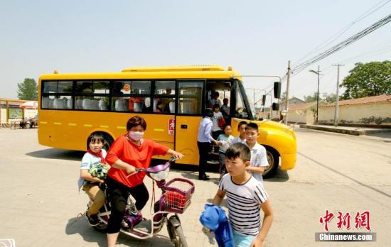 資料圖：學(xué)生家長接送從校車上下來的學(xué)生,。 張道正 攝
