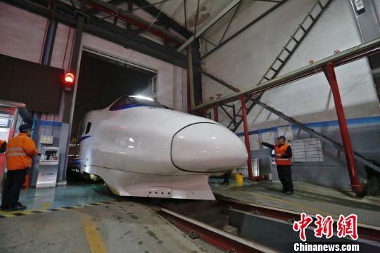 一列動車組駛入車庫，機械師位列兩邊檢查車體外觀,?！《〔?攝