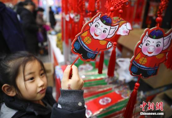 1月23日,，正在北京全國農(nóng)業(yè)展覽館舉辦的2019老北京年貨大集人頭攢動(dòng),、熱鬧非凡,。全國各地區(qū)優(yōu)質(zhì)特色產(chǎn)品及民俗文化在此一一呈現(xiàn),，給北京市民帶來精彩紛呈的購物體驗(yàn),。圖為小女孩被年貨大集上的豬年福牌吸引,。<a target='_blank' href='http://www.chinanews.com/'>中新社</a>記者 趙雋 攝