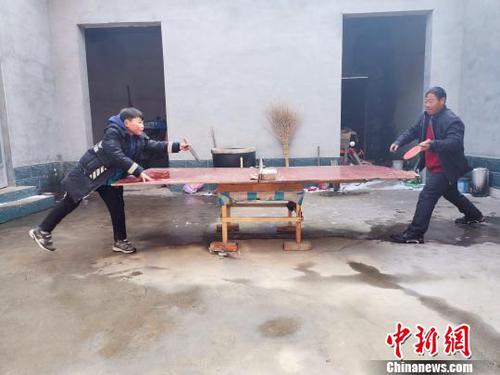 圖為劉奉智父親用自制的乒乓球臺(tái)陪劉奉智打乒乓球,?！『聦W(xué)娟 攝