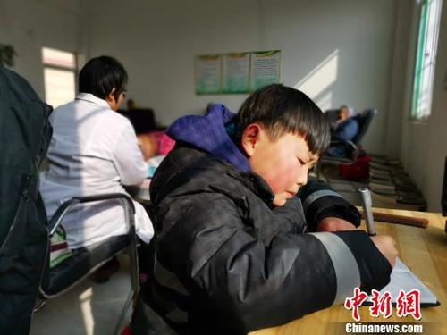 在社區(qū)服務(wù)中心,，劉奉智母親為村里人按摩，劉奉智在一旁寫(xiě)作業(yè),?！『聦W(xué)娟 攝