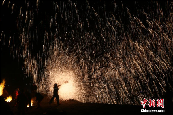 該村“打樹花”的習(xí)俗已延續(xù)了近600年，村民將生鐵融成鐵水后,，再用特制的木板將鐵水擊打至樹上,，頓時綻放出萬點“鐵花”。中新社記者 陳昊 攝