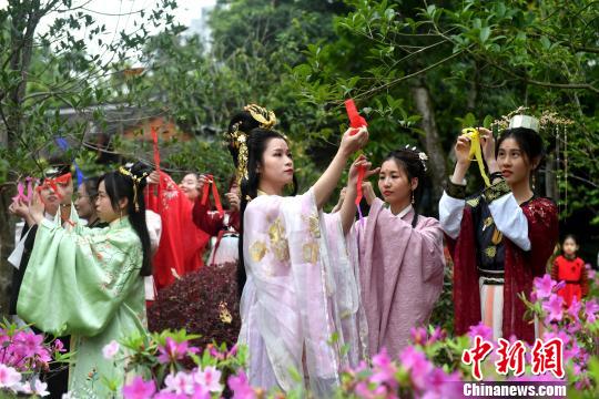 福建漢服少女將將寫有對春日祝福的彩帶系在百花枝頭,，共同送上美好的祝愿,。　呂明 攝