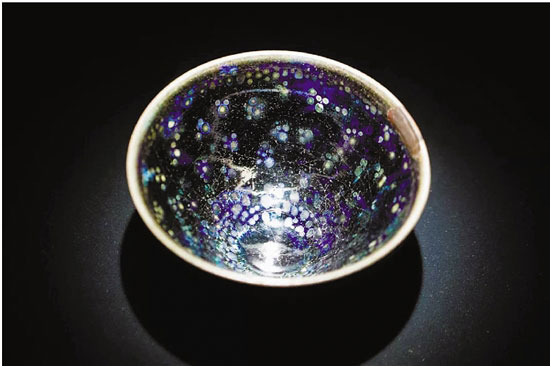 宋 曜變天目建盞（1951年定為日本國(guó)寶）
口徑: 12.2cm 高度: 6.4cm 藏于大德寺龍光院
束口,、深腹，釉斑隨著光線變化色澤,，黑斑點(diǎn)外套著藍(lán)紫色光環(huán),，具有幽玄之美,。據(jù)傳這件曜變?cè)诿鞒瘋鞯饺毡荆驱埞庠旱膭?chuàng)建者江月宗玩所有,，1606年被視為鎮(zhèn)院之寶,，作為佛器供奉。
