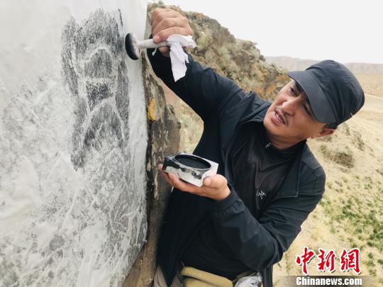 圖為杜成峰按照巖畫線條走向用拓包開始描邊,。　朵丹 攝