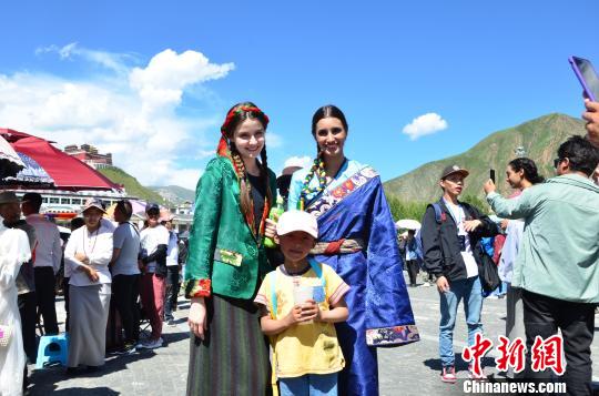 圖為身著藏族服裝的外籍模特比賽完與當(dāng)?shù)氐男『⒑嫌傲裟??！◆數(shù)り?攝
