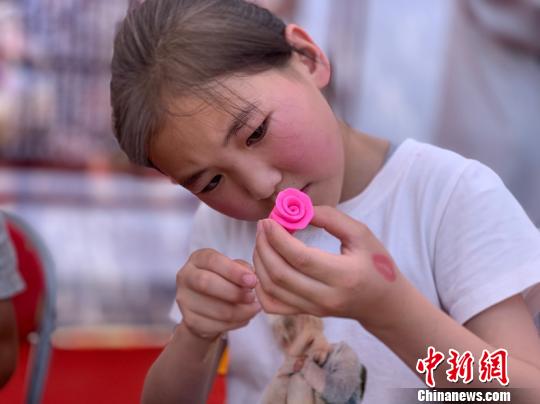 圖為小女孩正在用米塑捏玫瑰花,。　孫睿 攝