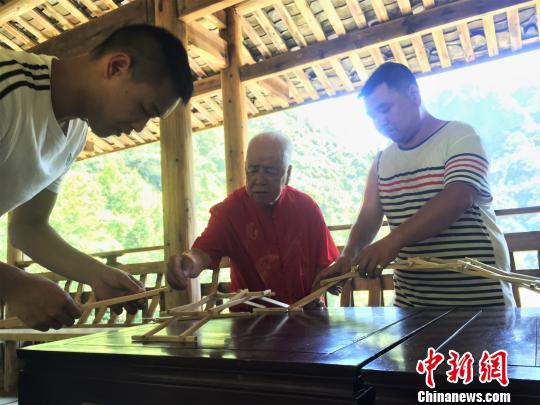 圖為黃春財(cái)與兒子,、孫子共同演示木拱廊橋搭建,。　葉茂 攝