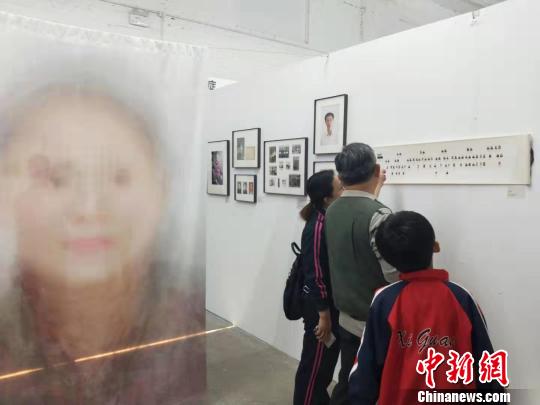 在第19屆中國平遙國際攝影大展柴油機展區(qū)的一角,，一張大幅的人像彩畫吸引來往游客駐足拍照?！钆迮?攝