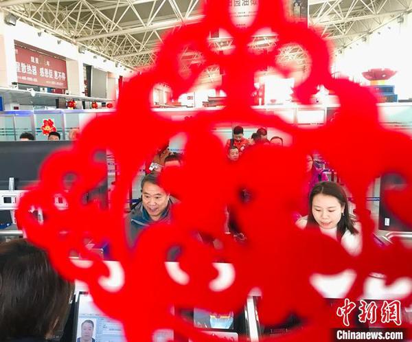 “春節(jié)裝飾”扮靚出入境邊防檢查執(zhí)勤現(xiàn)場,。圖為民眾排隊通過驗證臺?！“瑧c龍 攝