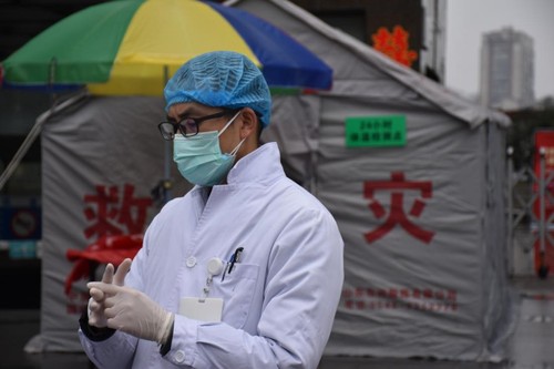 戴上一次性手套,、一次性口罩、一次性帽子,，穿著白大褂的譚曉鵬開始了一天的工作