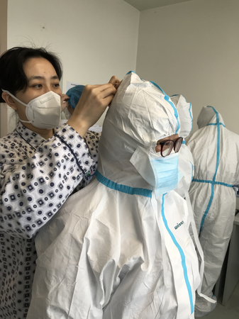3  王泠（左后）在為護(hù)理隊(duì)員仔細(xì)整理防護(hù)服,，叮囑她們?cè)谧龊霉ぷ鞯耐瑫r(shí)一定要注意保護(hù)好自己,。