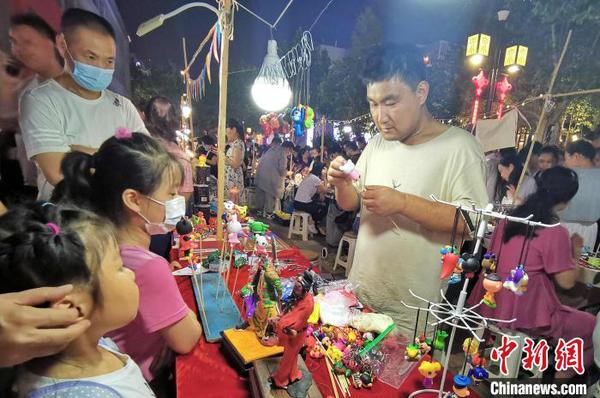 資料圖：圖為手工藝人在夜晚走上街頭，展示面塑工藝,。　趙曉 攝