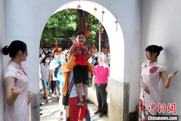 福州市民體驗(yàn)頭頂狀元道的門梁中間懸掛的粽子，寓意“粽狀元,，一舉高粽”?！∮浾邉⒖筛?攝