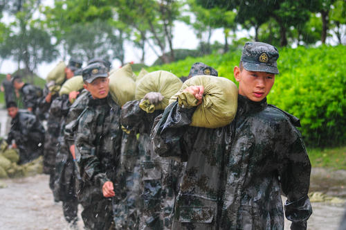 圖為在安徽合肥巢湖任務(wù)區(qū)官兵在暴雨中扛運(yùn)沙袋，加固堤壩,。（王文洲 攝）