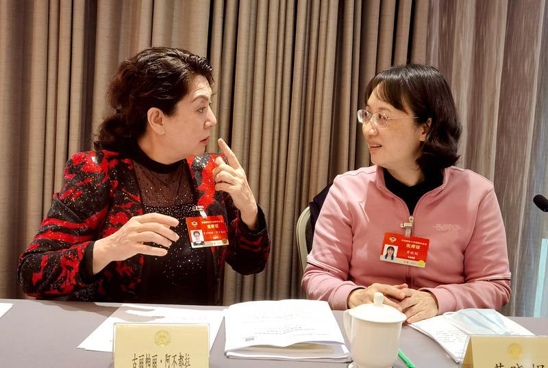 古麗帕麗?阿不都拉委員（左）和黃曉娟委員就提案各抒己見(jiàn),。 特邀委員記者 唐江澎攝
