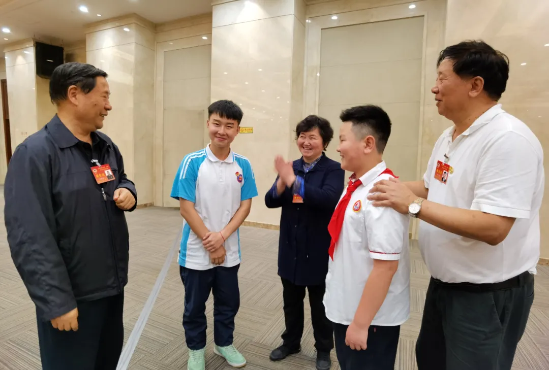 全國政協(xié)常委戚建國（左一）、全國政協(xié)文化文史和學(xué)習(xí)委員會(huì)副主任葉小文（右一）與學(xué)生親切交談