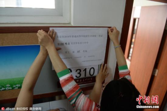 2016年6月3日，北京,，東直門中學(xué)考點(diǎn),，教室外已貼上了統(tǒng)一印制的考場(chǎng)信息，上面顯示著考點(diǎn)編號(hào),、名稱及具體的考場(chǎng)號(hào),。教室內(nèi)設(shè)置了約30個(gè)考生座位，座位與座位之間的距離約為80厘米以上,。兩位考務(wù)老師手持一疊寫有學(xué)生姓名,、準(zhǔn)考證號(hào)的桌簽走進(jìn)教室，按考場(chǎng)座位安排表逐一貼在桌子上,。隨后,，一位老師在黑板上寫下了當(dāng)科開考的科目、考試時(shí)間和試卷份數(shù),。圖片來源：東方IC 版權(quán)作品 請(qǐng)勿轉(zhuǎn)載
