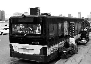 路邊停放的公交車頂上的空調(diào)十分顯眼，旁邊碼放著座椅、遮陽棚,、啤酒等物,?？导?攝